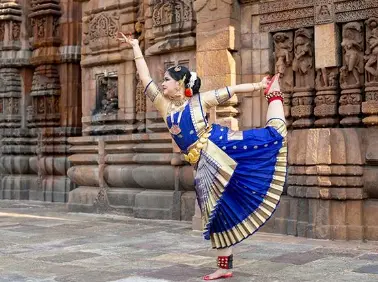 Bharatanatyam dancer performing in traditional costume at a historic temple in India